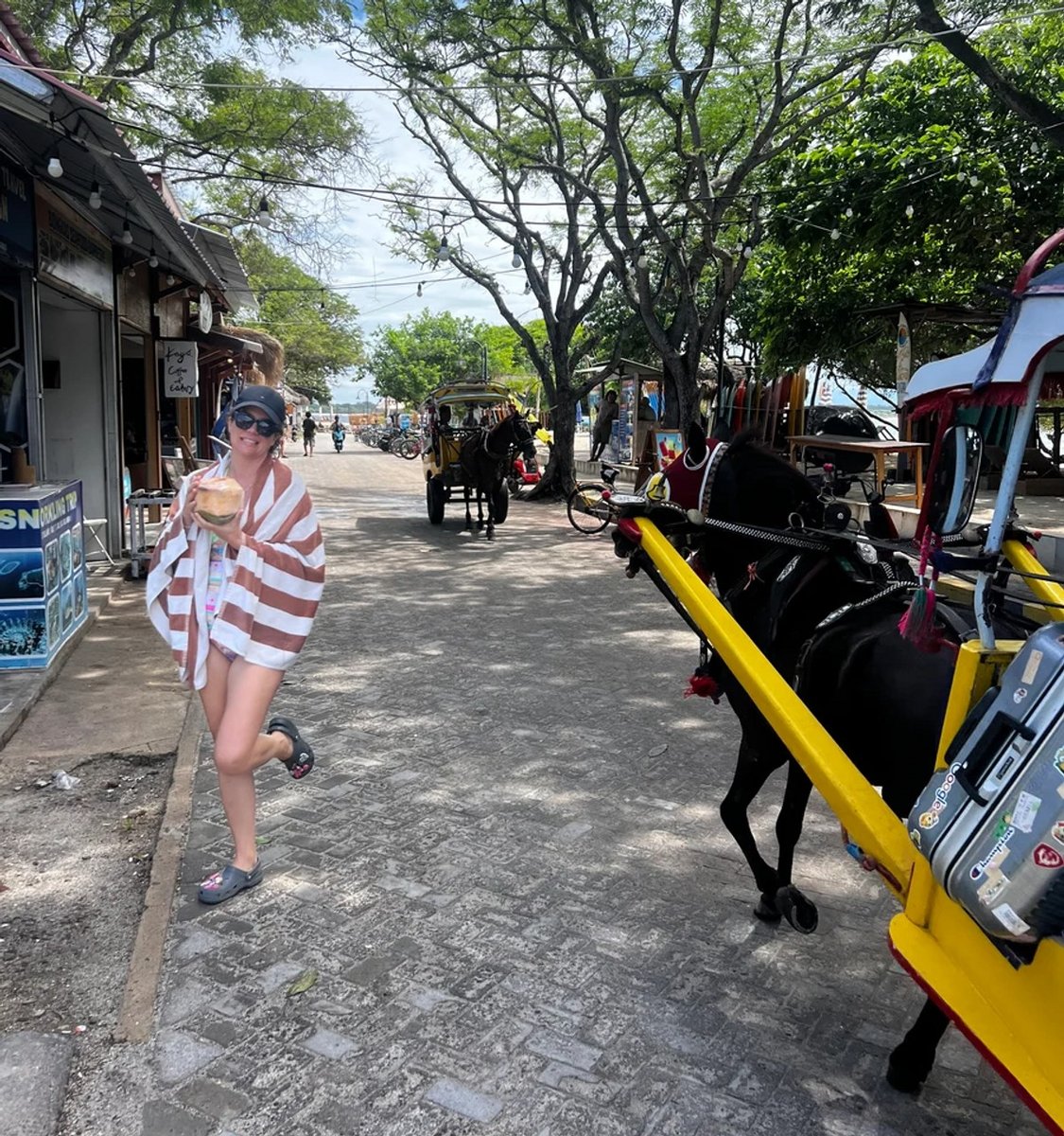 woman holding coconut next to horse and carts