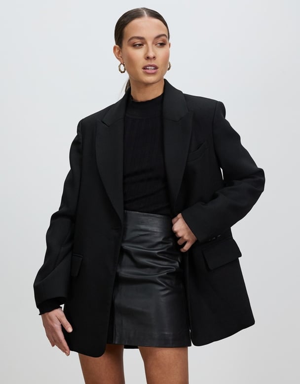 Woman wearing black oversized blazer and skirt. 