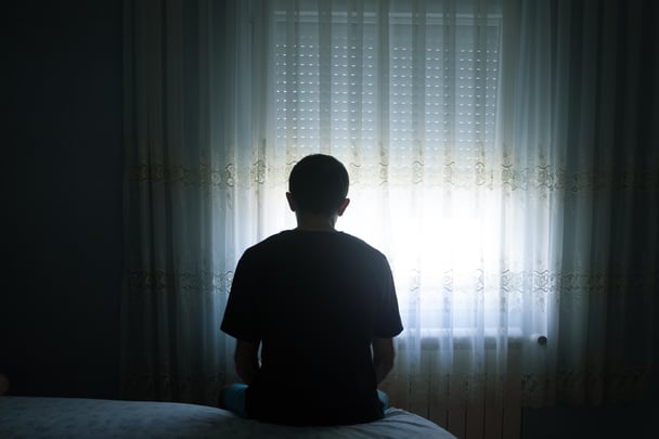 A lonely man sits alone in a dark room.