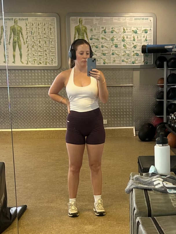 Lucy taking a mirror selfie in the gym in activewear.