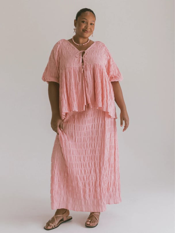 Model in pink shirt and skirt set.