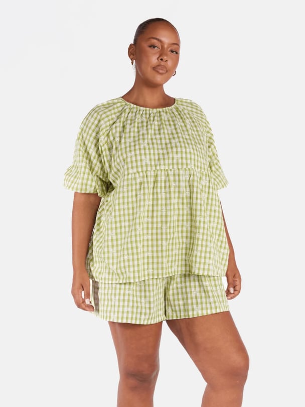 Model in lime green gingham smock shirt with puffy sleeves.