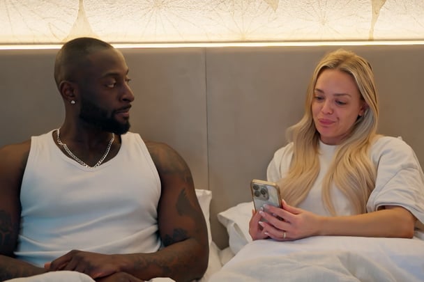 Alissa reading David messages in bed.