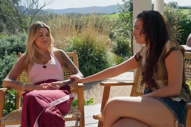 Juliette touches Gia's arm as they chat.