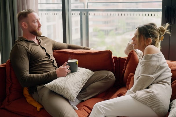 Bec and Danny chat on their couch.