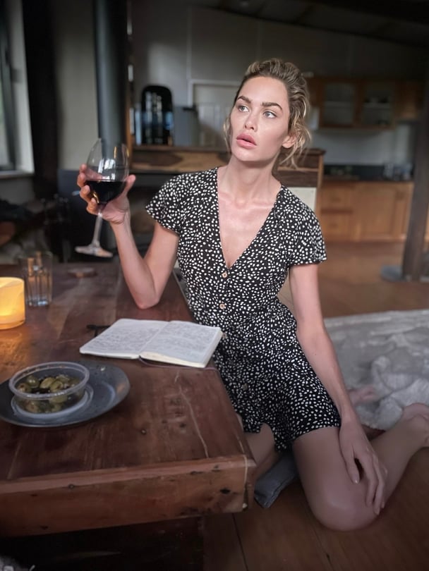 Megan at home in her living room, holding a glass of wine.