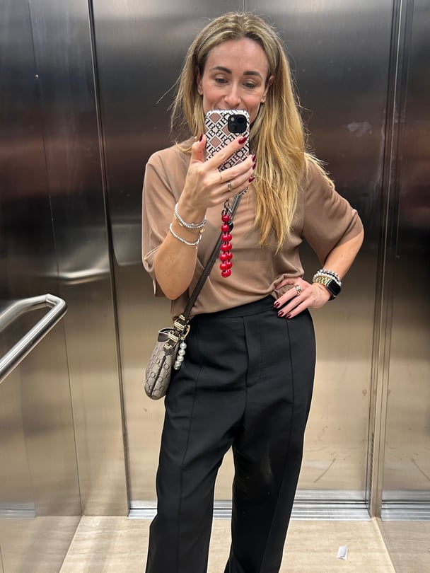 Mirror selfie of Mollie in brown t-shirt and black pants.