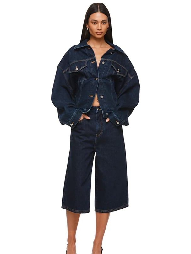 Woman wearing an oversized, structured denim jacket with wide, voluminous sleeves and a cropped hem and high-waisted denim culottes with a wide-leg silhouette from Nakedvice.