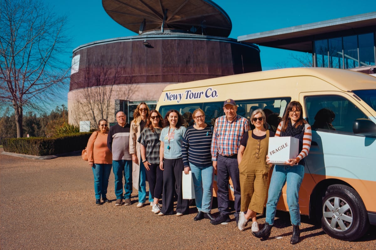 Group of people in front of a 'Newy Tour Co.' van.,