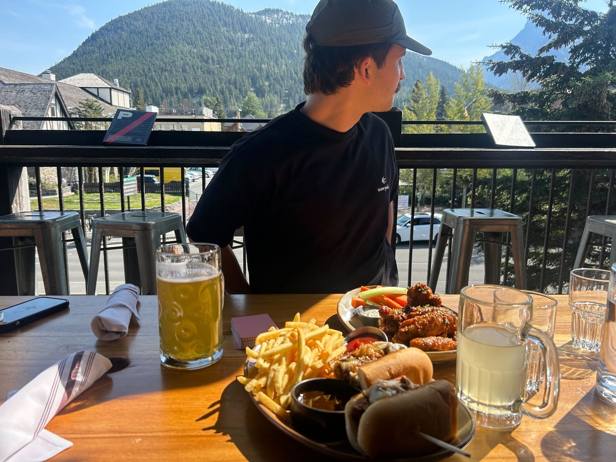 Dining table overlooking mountains in Banff with burgers, wings and beers.