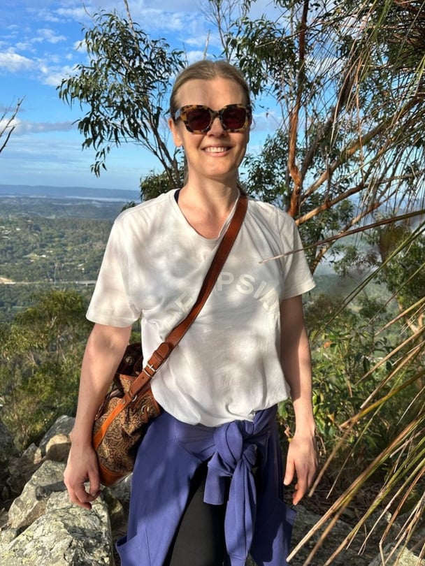 Pip smiles in activewear in nature.