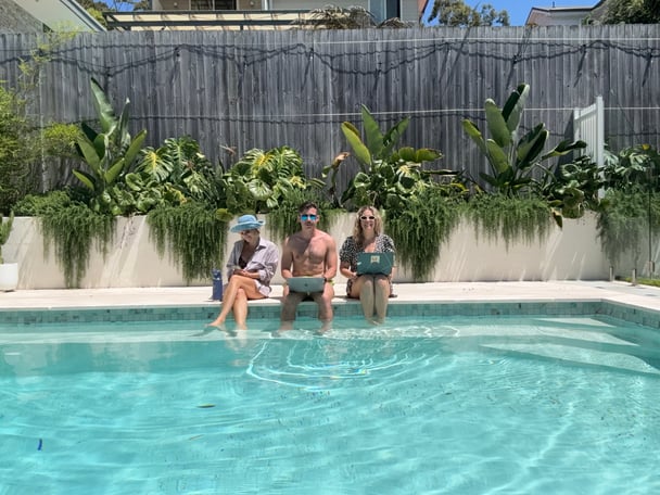 3 people sitting by a pool 