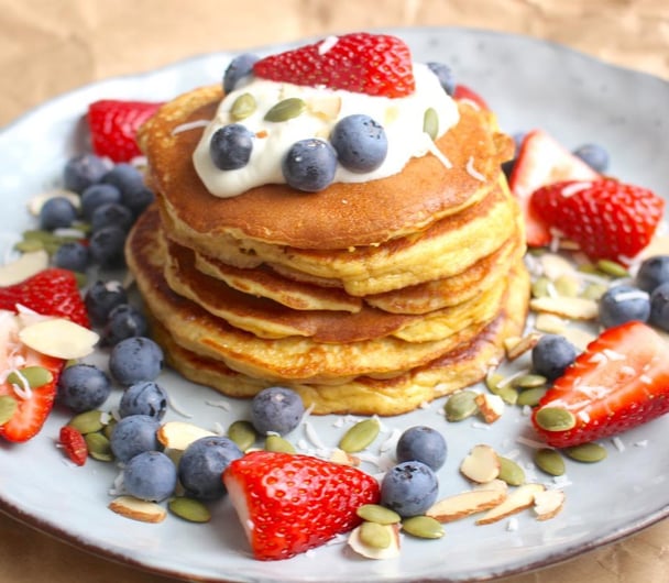 A stack of Weet-Bix and banana pancakes with strawberries, blueberries, seeds and yoghurt.