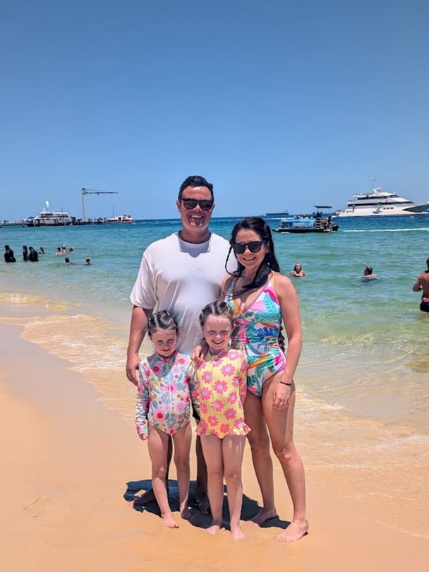 Rebecca with her husband and their two young girls at the beach.