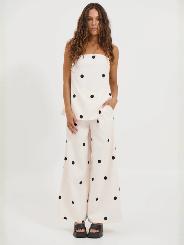 Model wears two piece, strapless black and white set, with pants.