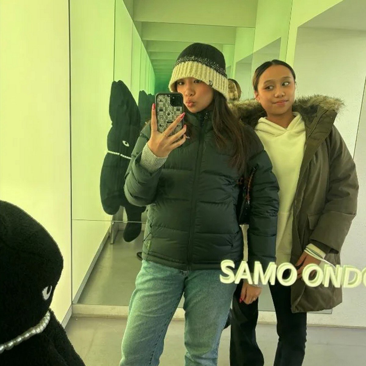 Two girls posing in front of mirror.