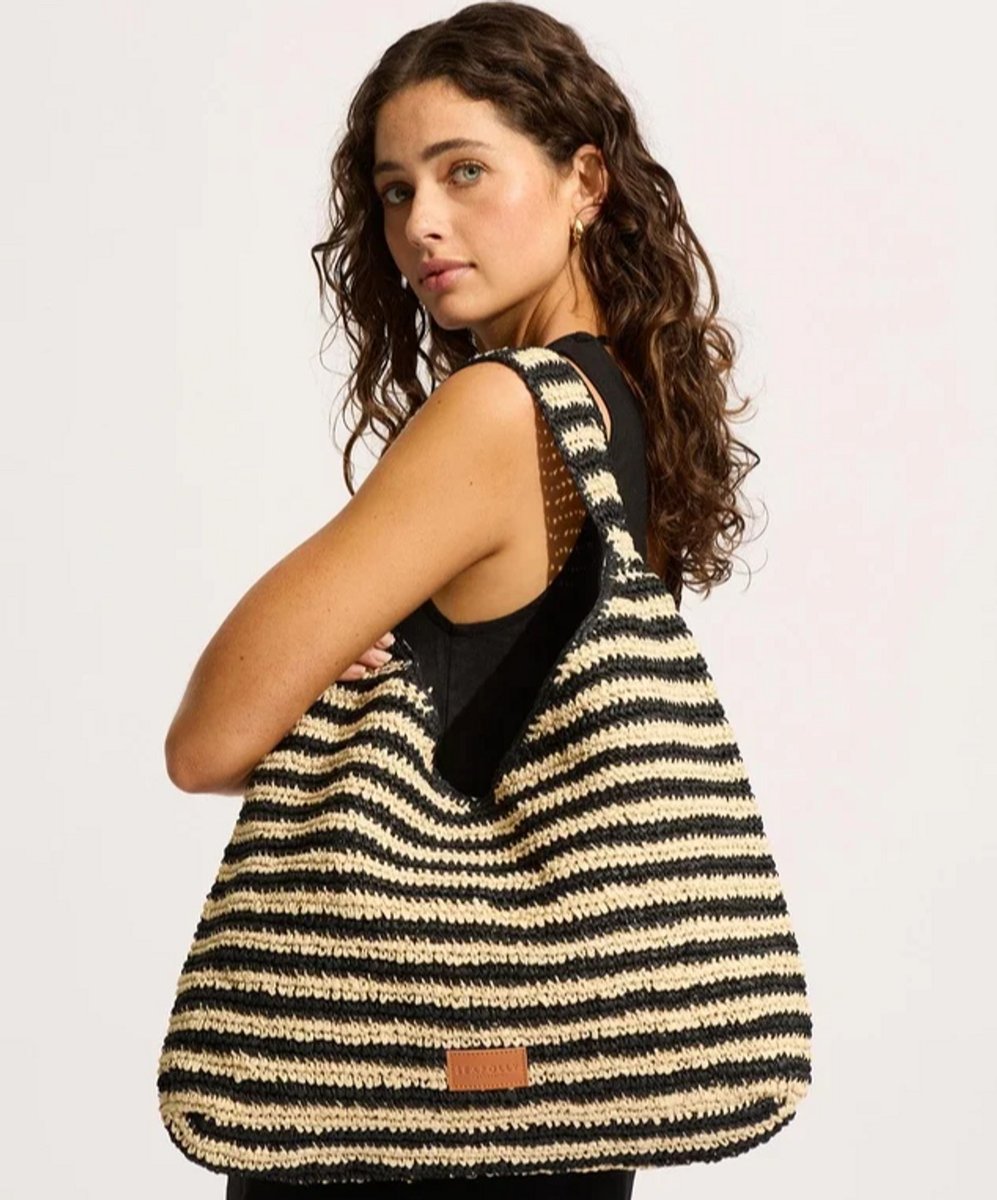 woman wearing large rafia tote bag with stripes