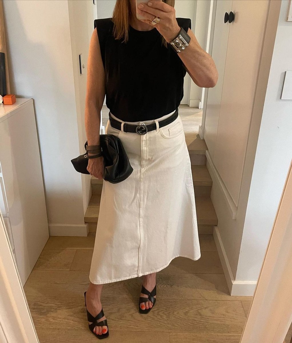 Woman wearing white denim midi skirt.