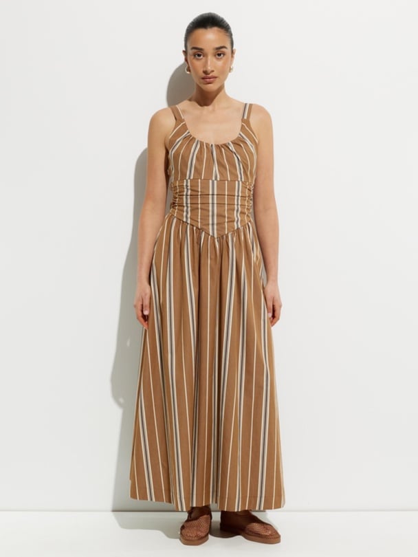 Model wears a camel coloured maxi dress with white and grey stripes.