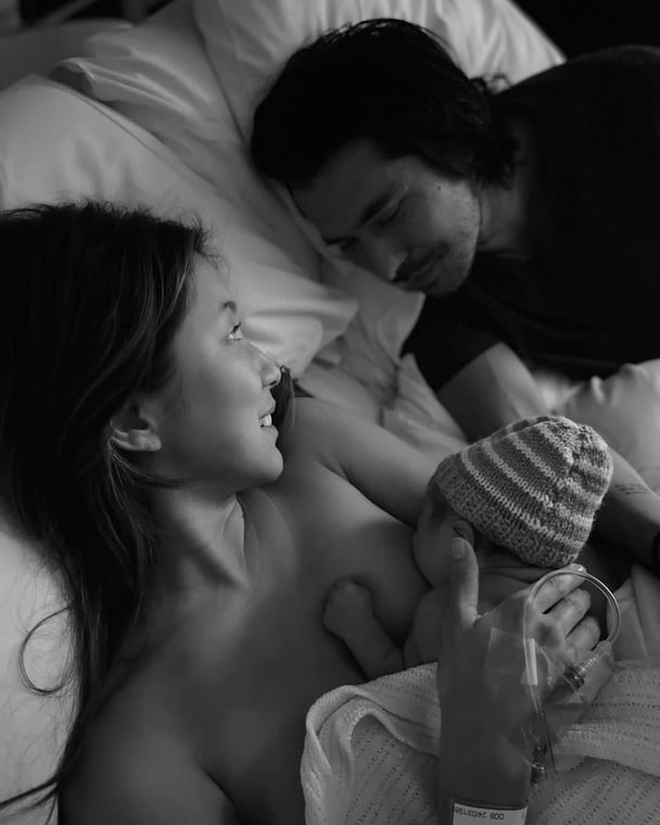 A black and white image of a woman with her husband after giving birth to their son.