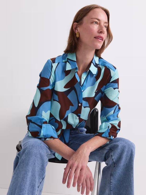 Model sitting down in brown shirt with light and dark blue shapes.