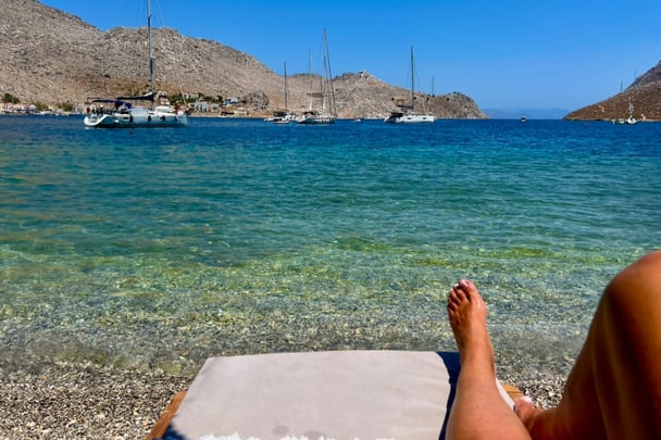 POV photo of Meaghan reclining on a beach in Greece.
