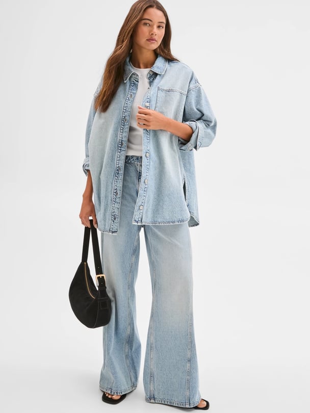 Woman wearing a relaxed light-wash oversized shirt and wide leg jeans from Target.