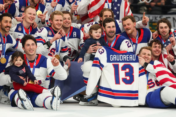 Johnny Graudeau's two oldest children pose for a photo on the ice with Team USA after they win gold at the Milan Cortina Olympic Games.,