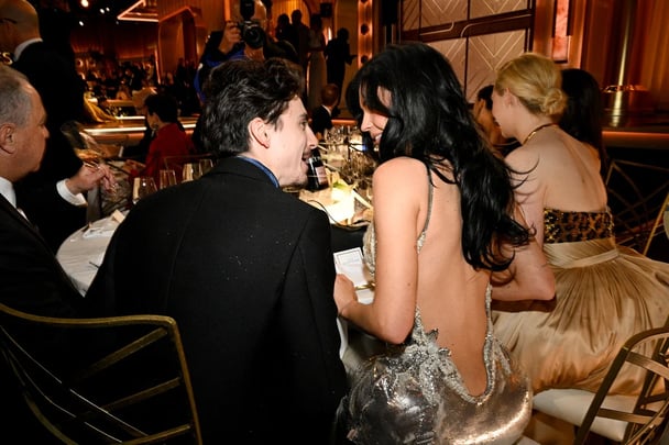 Timothee Chalamet, wearing a black blazer and blue scard, and Kylie Jenner, in a silver chainmail dress, cosying up at the 2025 Golden Globes.