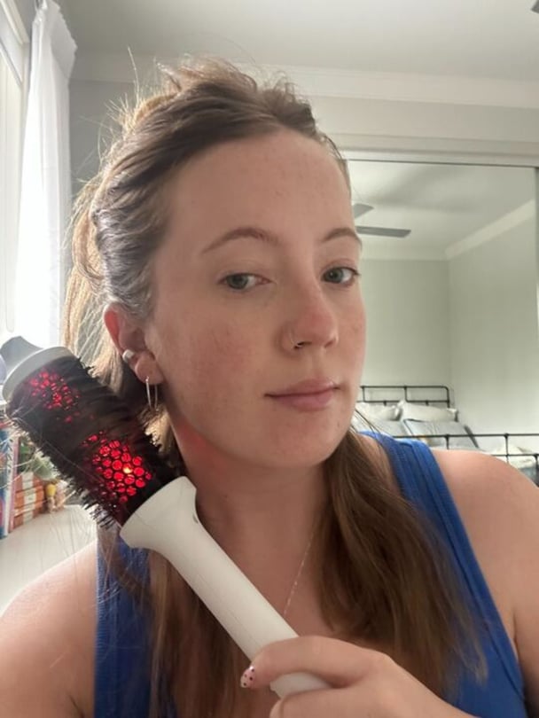 Selfie of Lucy holding thermal brush at 45 degree angle with hair wrapped around.