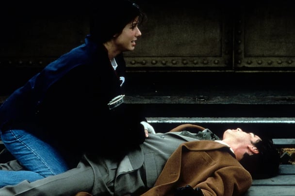 Sandra Bullock and Peter Callaghan on the train tracks in a scene for While You Were Sleeping.