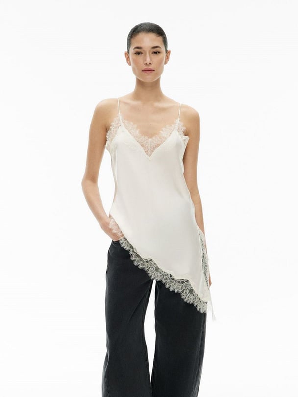 Model in mid-length white camisole with lace trim.