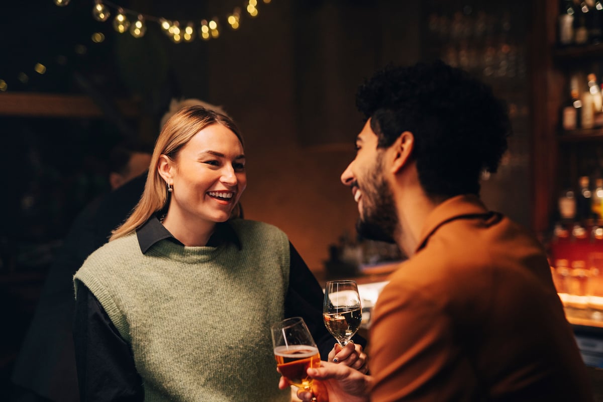 A woman and a man sit at a bar smiling.