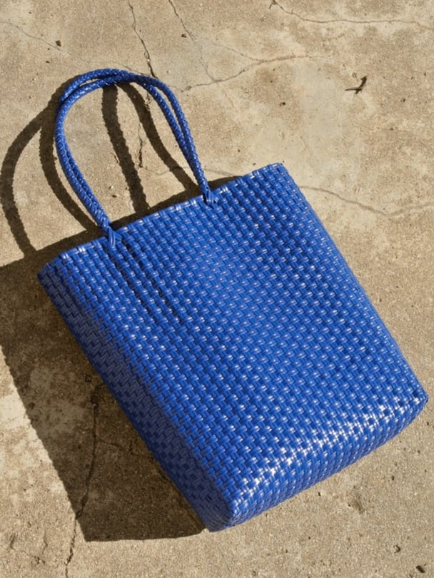 Cobalt blue woven tote bag laying on side.