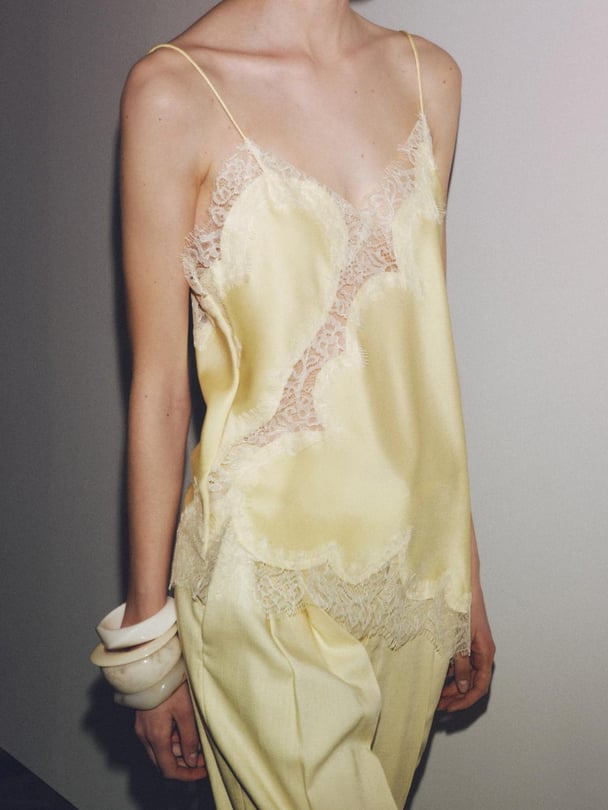 Model in yellow camisole top with lace trim.